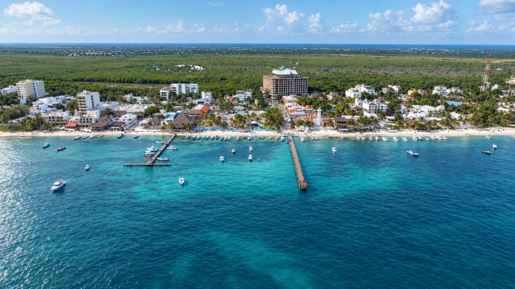 Aerial view of Puerto Morelos: the town, its beach and two piers with fishing boats moored in turquoise water